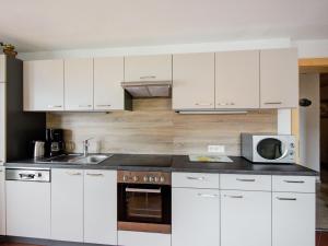 a kitchen with white cabinets and a microwave at Scenic Apartment in Tirol with Garden in Kaltenbach