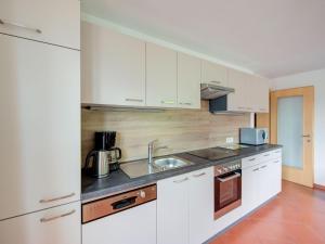 a kitchen with white cabinets and a sink at Scenic Apartment in Tirol with Garden in Kaltenbach