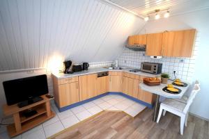 eine kleine Küche mit einem Tisch und einem TV in der Unterkunft Ferienwohnung Langeoog in Neuharlingersiel + 10 Fotos