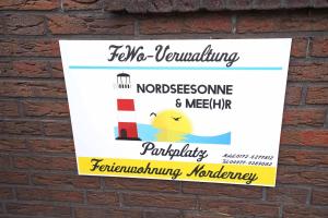 ein Schild an einer Backsteinmauer mit einem Leuchtturm in der Unterkunft Ferienwohnung Langeoog in Neuharlingersiel