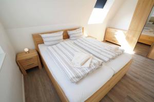 ein Schlafzimmer mit einem großen weißen Bett mit gestreifter Bettwäsche in der Unterkunft Ferienhaus Lüttje Krabbe in Carolinensiel