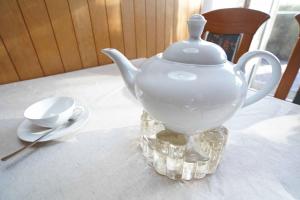 eine weiße Teekanne auf einem Tisch neben einem Löffel in der Unterkunft Ferienwohnung Käp` tns in Dornumersiel