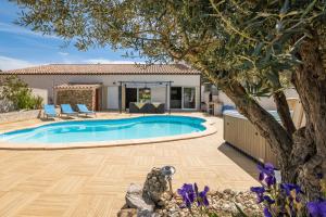 um quintal com uma piscina e uma árvore em Villa avec piscine et Jaccuzy em Bize-Minervois