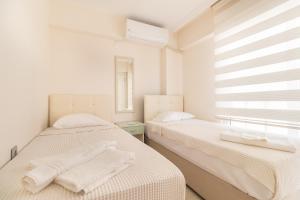2 Betten in einem Zimmer mit weißen Wänden und einem Fenster in der Unterkunft Apartments Near to City Center and Beach in Marmaris