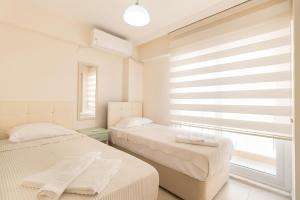 2 Betten in einem weißen Zimmer mit Fenster in der Unterkunft Apartments Near to City Center and Beach in Marmaris