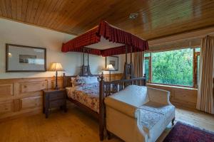 a bedroom with a canopy bed and a chair at StayVista at The Imperial Estate with scenic views in Nagar