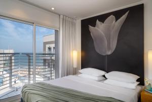 een slaapkamer met een groot bed en een groot raam bij Savoy Sea Side Hotel in Tel Aviv