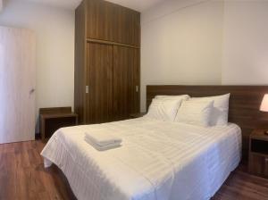 a bedroom with a large white bed with a wooden headboard at Charm City Apartment Di An Binh Duong in Dĩ An +8 photos
