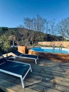 uma piscina com duas mesas de pingue-pongue num deque em L Atelier gîte 3 étoiles avec piscine Le Jas des Oliviers em Le Castellet