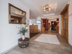 a hallway with a mirror and a vase of flowers at Hotel Vier Jahreszeiten by VAYA in Kaprun