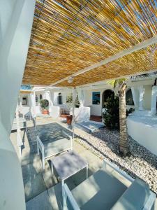 a patio with a wooden roof and chairs and a palm tree at B&B Villa D'Amato in Peschici