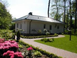 una pequeña casa blanca en un jardín con flores en Ferienhaus am Meer Katharinenhof, en Katharinenhof