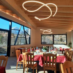 a dining room with tables and chairs and a chandelier at Pier Hotel in Andalo