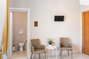 two chairs and a table in a room with a toilet at Il 49 Rooms Noto in Noto