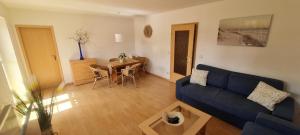 a living room with a blue couch and a table at Am Walde in Trassenheide