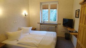 um quarto com uma grande cama branca e uma televisão em Die Kapelle Bed & Breakfast em Bad Liebenstein