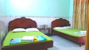 a bedroom with two beds with green sheets at Thuy Hang Motel in Long Hai