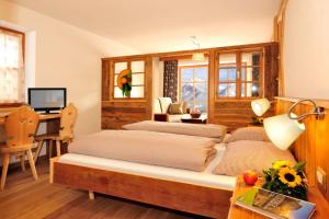 a bedroom with two beds and a desk at Agriturismo Soleseid in San Vigilio Di Marebbe