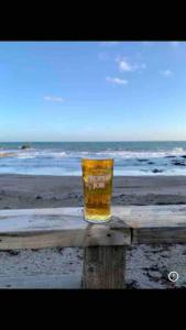 a glass of beer sitting on a wooden table at the beach at The Bolt Hole - Looe. in Looe