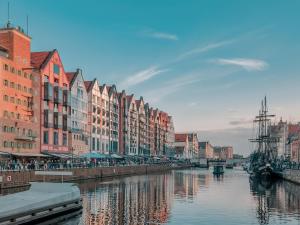a city with buildings and a river with a boat at Apartamenty Chmielna 10 - kompleks Deo - Old Town in Gdańsk