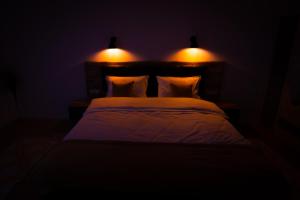 a dark room with a bed with two lights on it at Urban Six Apartments in Făgăraş