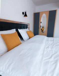 a bedroom with a large white bed with orange pillows at Urban Six Apartments in Făgăraş
