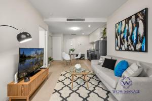 a living room with a couch and a flat screen tv at WOW Apartment on Collins in Melbourne