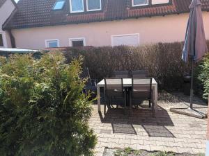 a table with chairs and an umbrella in front of a house at Binder's Ferienapartments zur Altmühl in Herrieden
