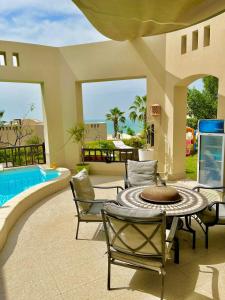 un patio con mesa, sillas y piscina en Private guest house in five stars resort en Ras al-Khaimah
