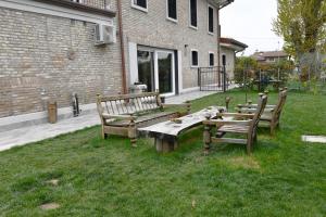 three wooden benches sitting in the grass next to a building at La Pineta del Borgo in Ravenna