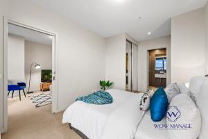 Un dormitorio con una cama blanca con almohadas azules. en WOW Apartment on Collins en Melbourne