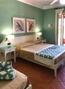two beds in a room with green walls at iGV Club Baia Samuele in Sampieri +66 photos