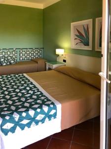 una camera con letto e parete verde di iGV Club Baia Samuele a Sampieri