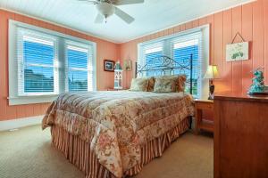 a bedroom with a bed and two windows at Rustic Oceanfront Cottage in Fernandina Beach