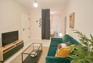 un soggiorno con divano verde e TV di Apartamentos Los Arroyos a Ponferrada