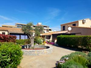una casa con un patio con un árbol. en Villa Calma Port Venus Village Naturiste Piscine & vélo en Cap d'Agde