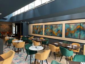 ein Restaurant mit Tischen, Stühlen und Gemälden an der Wand in der Unterkunft Hotel 55 in London