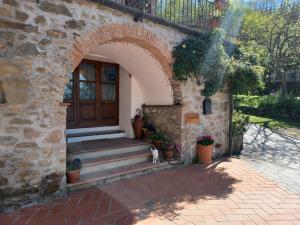 una entrada a una casa de piedra con un perro sentado en la puerta en LE PIANACCE - Appartamento per vacanze, en Castiglione di Garfagnana