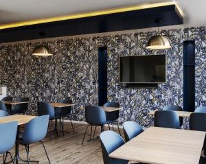 a restaurant with tables and chairs and a tv on a wall at Hôtel Le Windsor Biarritz in Biarritz