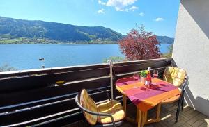 a table and chairs on a balcony with a view of a lake at ANNA Seeblick Appartement, Haus Hänsel&Gretel direkt am Ossiachersee mit Hallenbad, Skiarena Gerlitzen in Bodensdorf