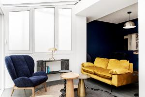 a living room with a yellow couch and blue chairs at Hôtel Le Windsor Biarritz in Biarritz