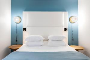 a bed with three pillows and two lights on top at Hôtel Le Windsor Biarritz in Biarritz