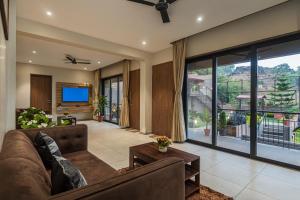 a living room with a couch and a large window at SaffronStays Cinco Elementos, Panchgani - stunning valley view pool villa in Panchgani
