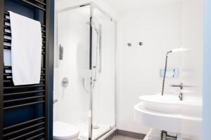 a bathroom with a glass shower and a sink at Hôtel Le Windsor Biarritz in Biarritz