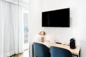 a room with a desk with a television and blue chairs at Hôtel Le Windsor Biarritz in Biarritz