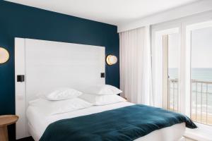 a bedroom with a bed with a blue accent wall at Hôtel Le Windsor Biarritz in Biarritz