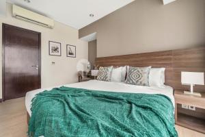 a bedroom with a large bed with a green blanket on it at Sonata by Kozystay - Pondok Indah in Jakarta +14 photos