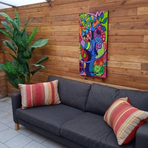 un sofá y dos pinturas en una pared de madera en Sweet home vintage, en Charleroi