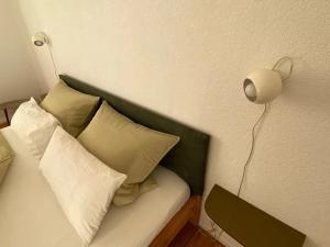a bed with pillows and a lamp on a wall at annadaly Stadtraumwohnung in Lörrach