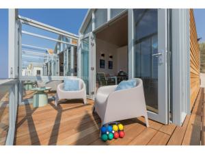 een balkon met twee stoelen en een tafel en wat ballen bij Cottage on the beach of Dishoek in Dishoek